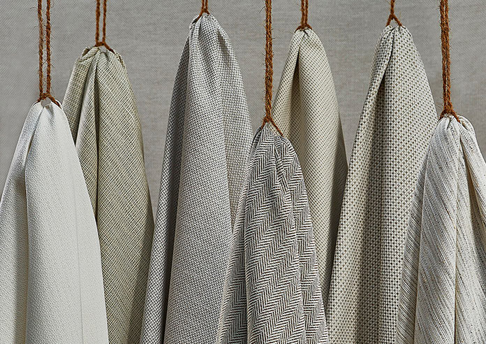 A collection of grey textured soft fabrics, hanging artfully on some twine.