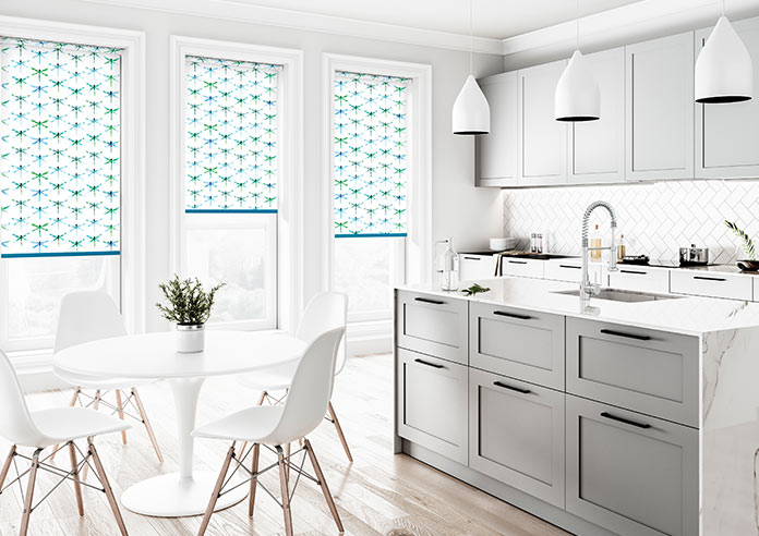 A green and blue dragonfly roller blind is shown in a clean, neutral kitchen/dining area.