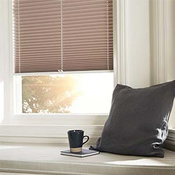 A warm brown pleated Perfect Fit blind, fitted in a uPVC bay window.