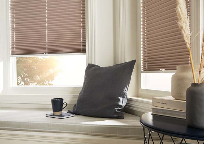A warm brown pleated Perfect Fit blind, fitted in a uPVC bay window.