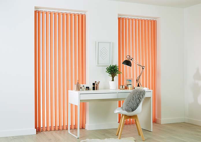 Coral orange vertical blinds, fitted in narrow windows in an office.