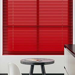 A red metal Venetian blind is centrepoint in a clean, black and white kitchen.