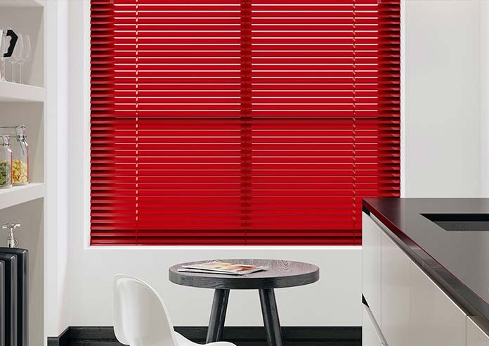 A red metal Venetian blind is centrepoint in a clean, black and white kitchen.