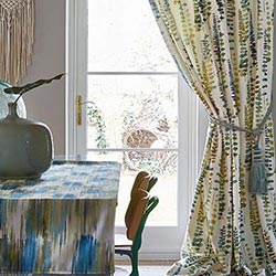 A botanical curtain is shown, drawn back from a white door.