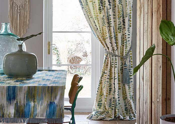 A botanical curtain is shown, drawn back from a white door.