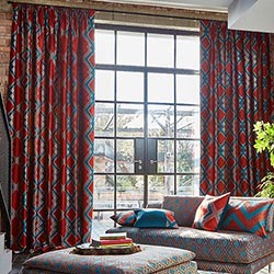 A blue and red curtain sites on a modern french door. Various luxiurious fabrics are shown off in the living room.