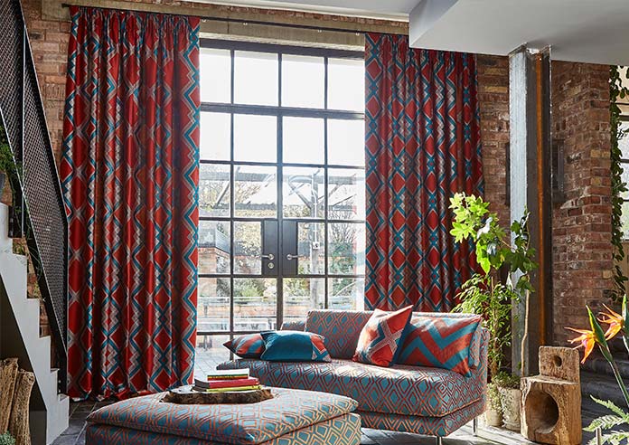 A blue and red curtain sites on a modern french door. Various luxiurious fabrics are shown off in the living room.