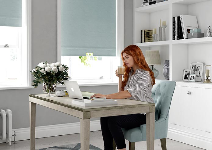 A red haired lady ordering blinds in a home office.