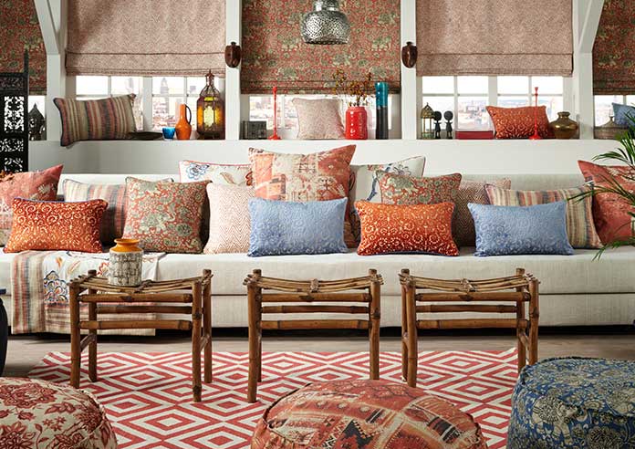 The room is decorated with various Moroccan-styled upholstery, throws and blinds. Each fabric is different and the scheme is mix of texture and red, orange and brown schemes.