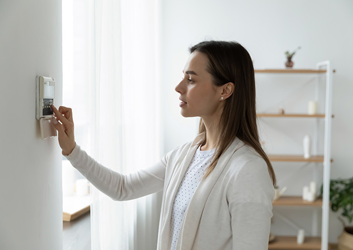 Side view of a young woman using smart home system