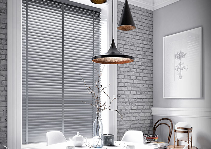 A kitchen is shown is a large window. Grey is the colour scheme. A wide grey wooden blind is shown on the window.